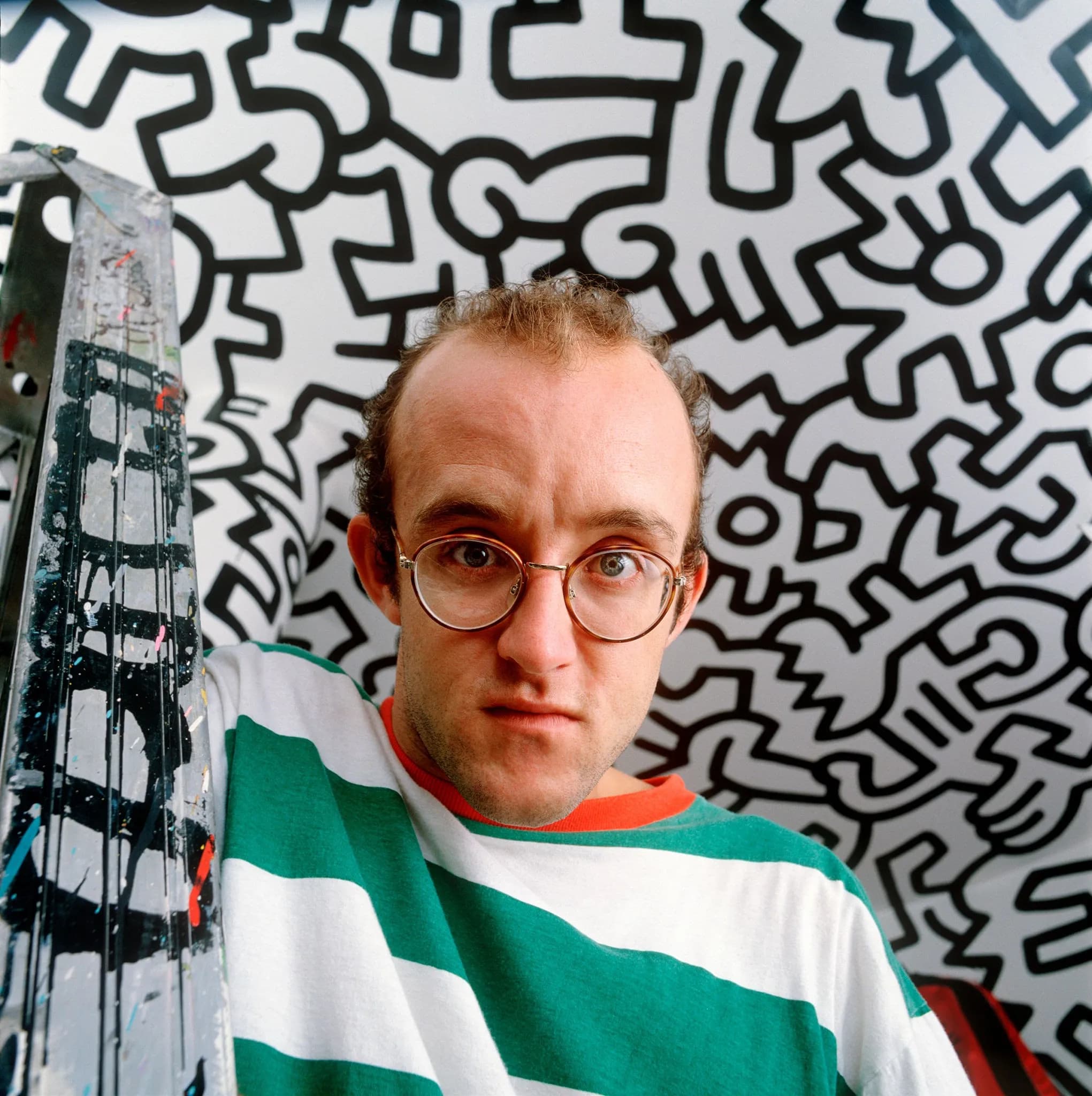 Keith Haring standing in front of one of his signature vibrant artworks.