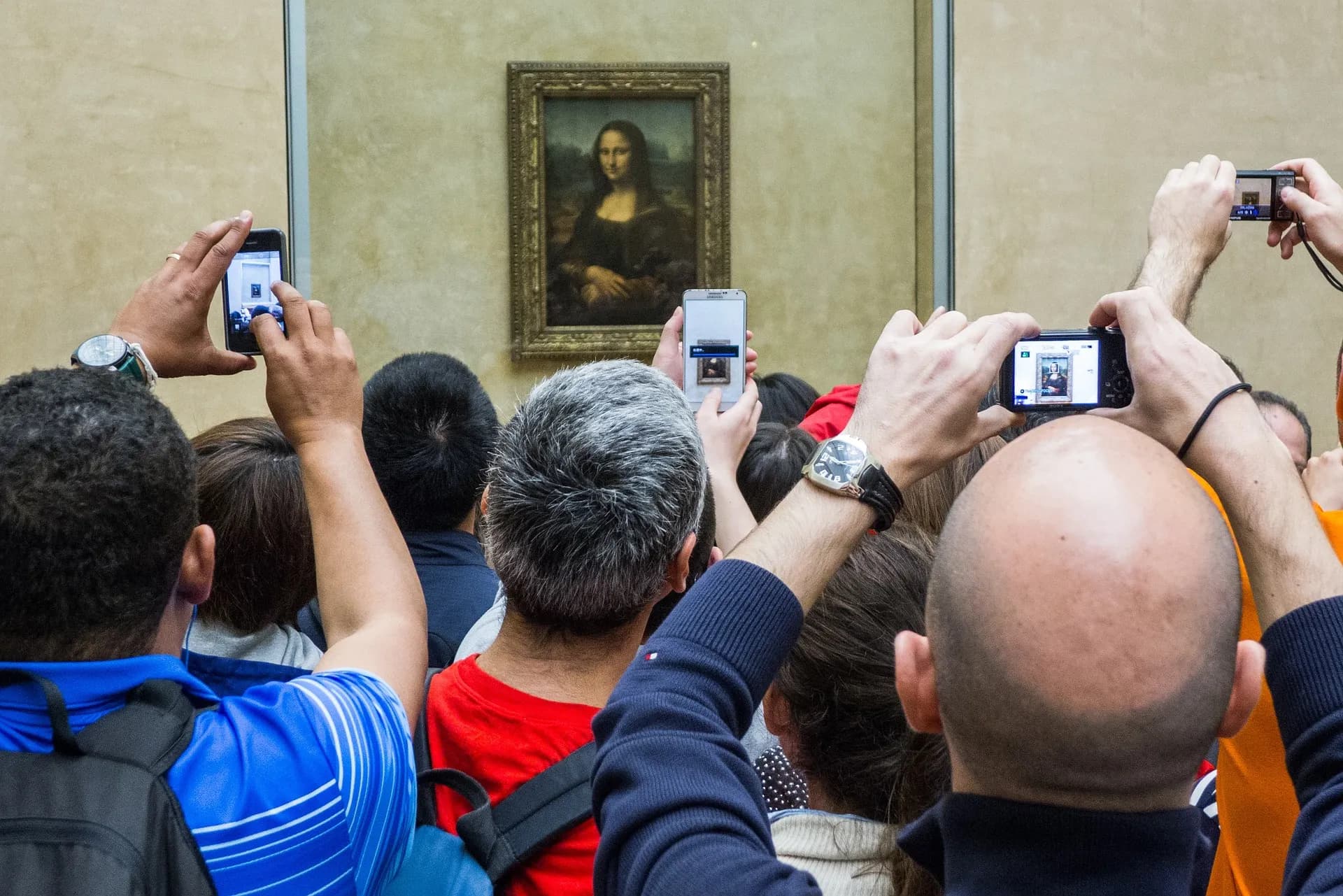 Tourists taking photos of the Mona Lisa, illustrating how art humanizes technology in the digital age.